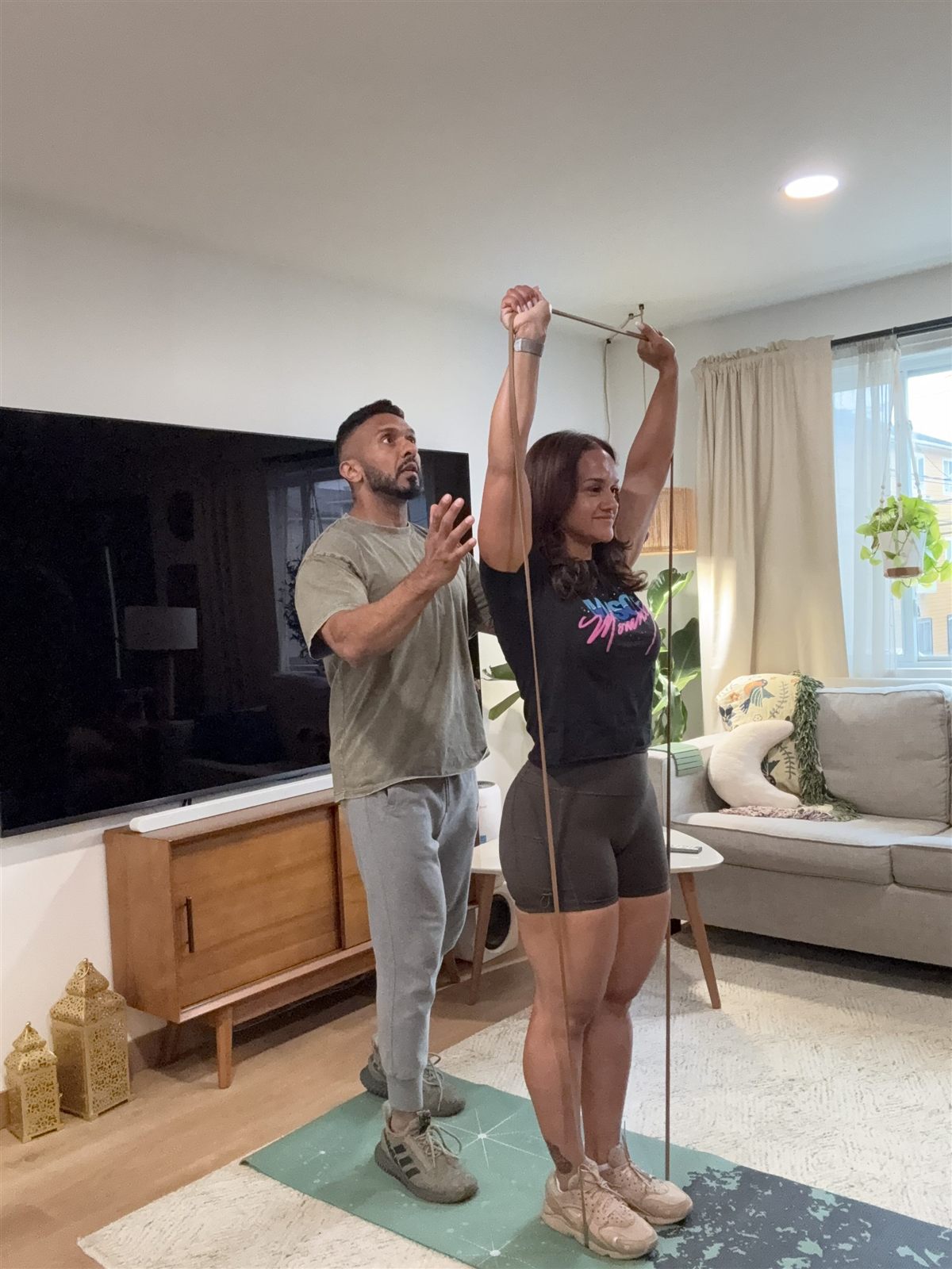 Jamal coaching a client through a band exercise in her living room