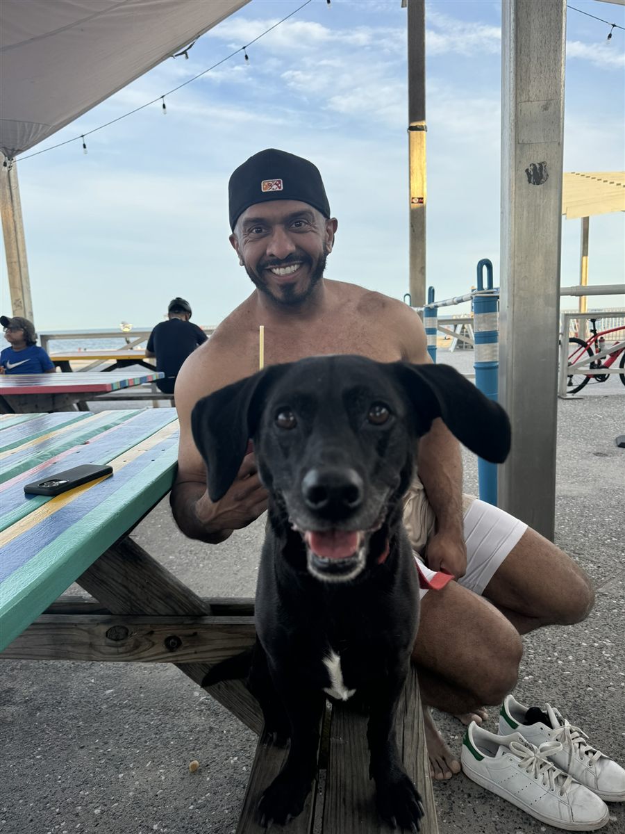 Jamal and his dog at a picnic table by the beach